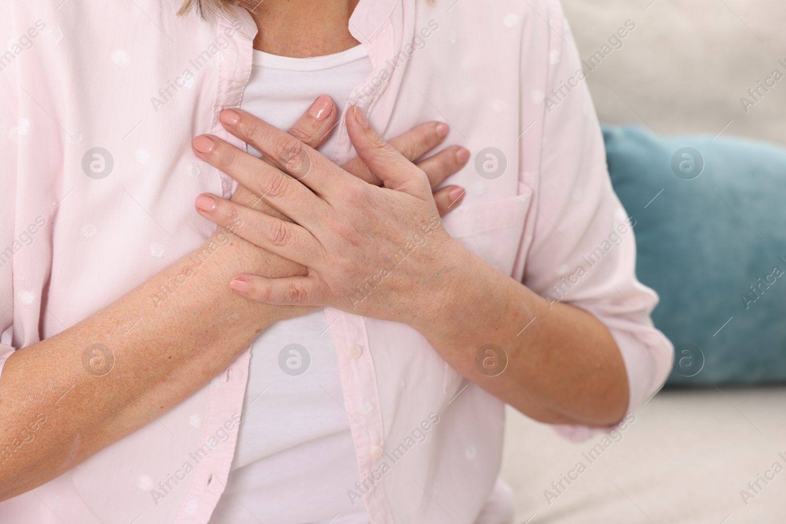 Photo of Heart attack. Senior woman suffering from pain in chest indoors, closeup