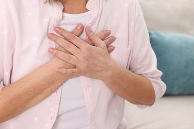 Photo of Heart attack. Senior woman suffering from pain in chest indoors, closeup