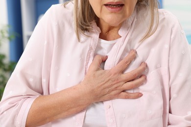 Heart attack. Senior woman suffering from pain in chest indoors, closeup