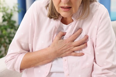 Heart attack. Senior woman suffering from pain in chest indoors, closeup