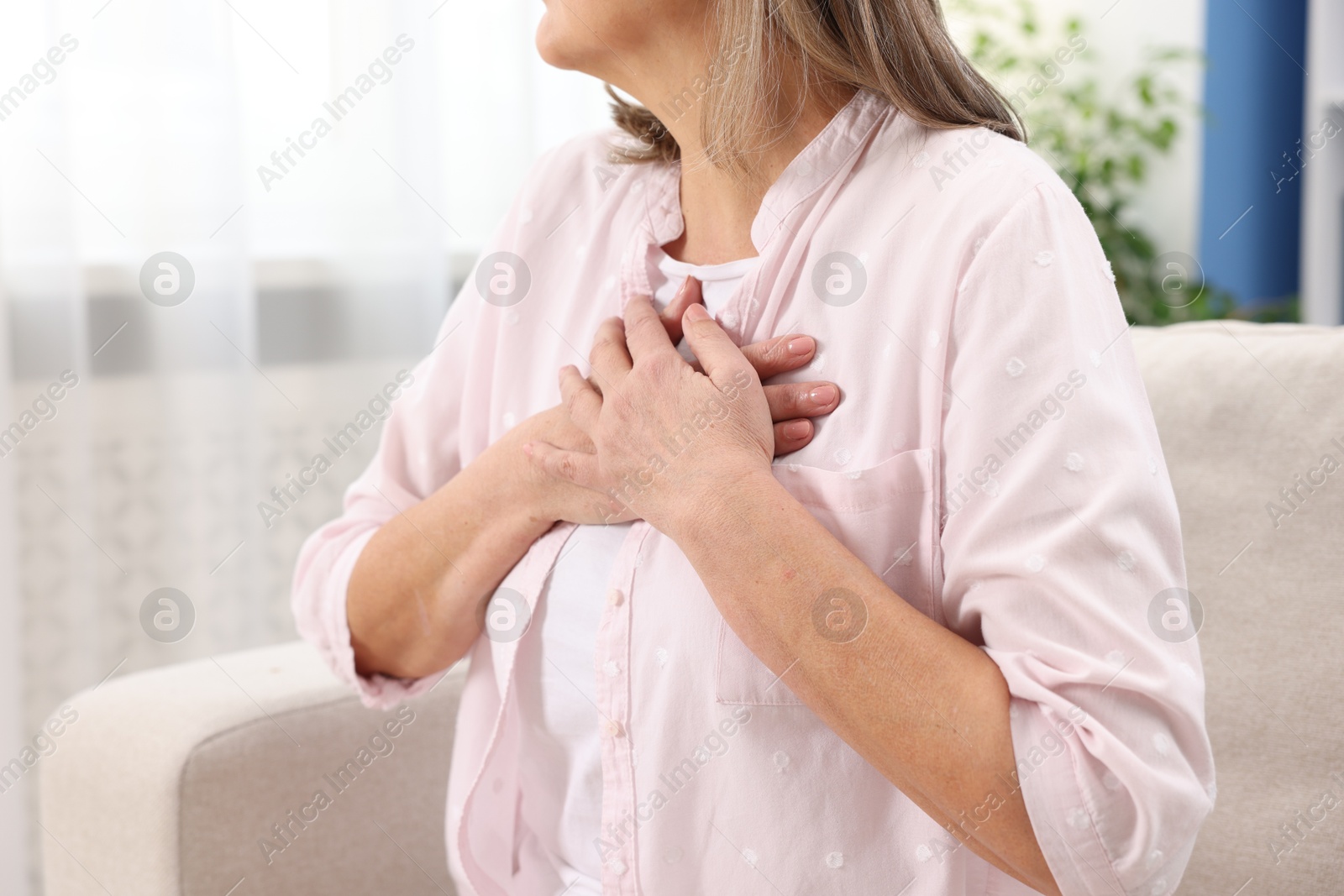 Photo of Heart attack. Senior woman suffering from pain in chest indoors, closeup