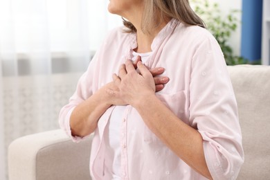 Heart attack. Senior woman suffering from pain in chest indoors, closeup