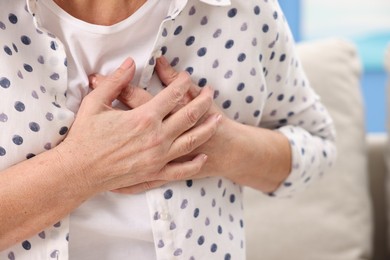 Photo of Heart attack. Senior woman suffering from pain in chest indoors, closeup