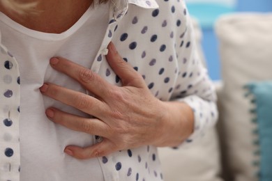 Heart attack. Senior woman suffering from pain in chest indoors, closeup