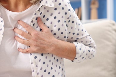 Photo of Heart attack. Senior woman suffering from pain in chest indoors, closeup