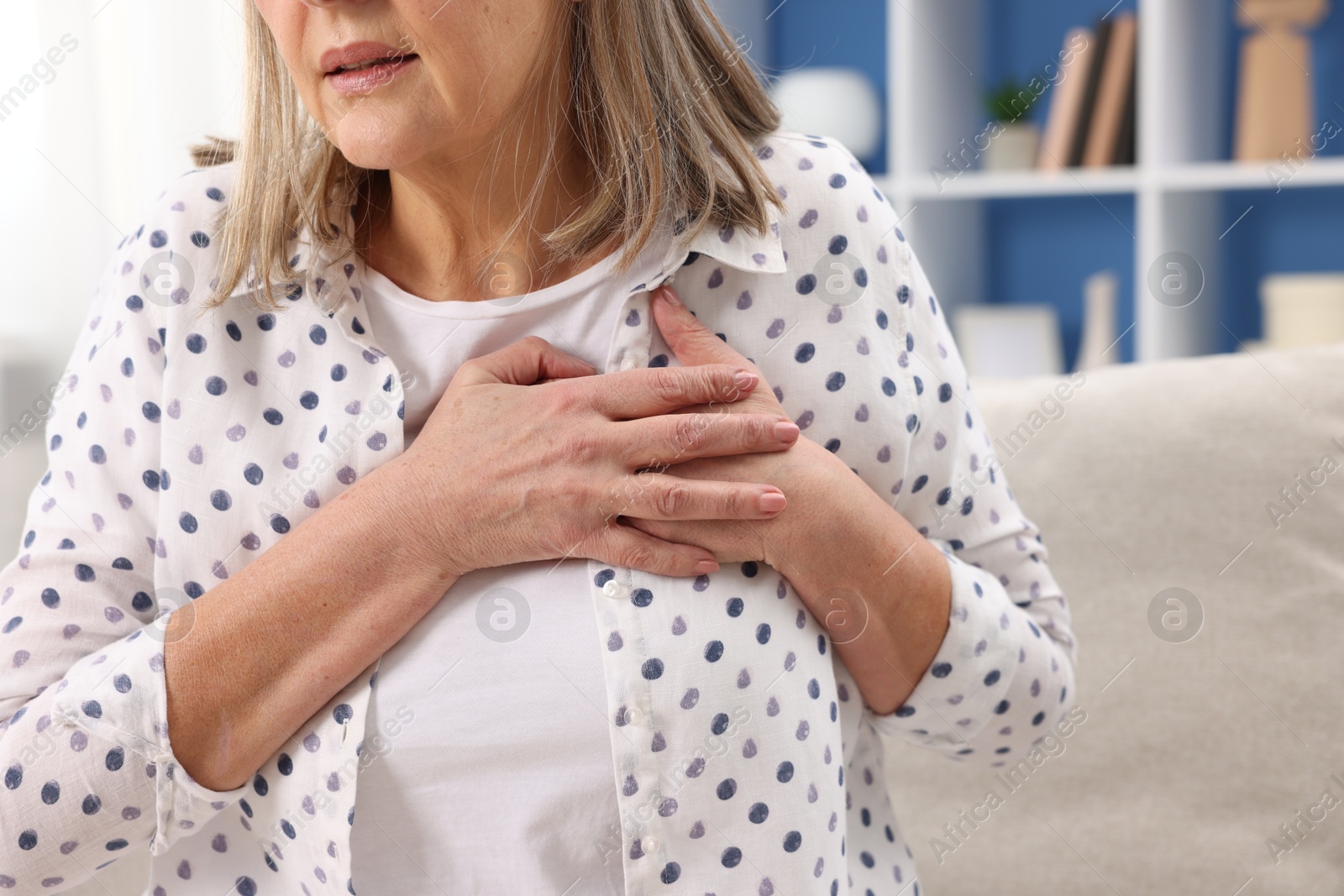 Photo of Heart attack. Senior woman suffering from pain in chest indoors, closeup