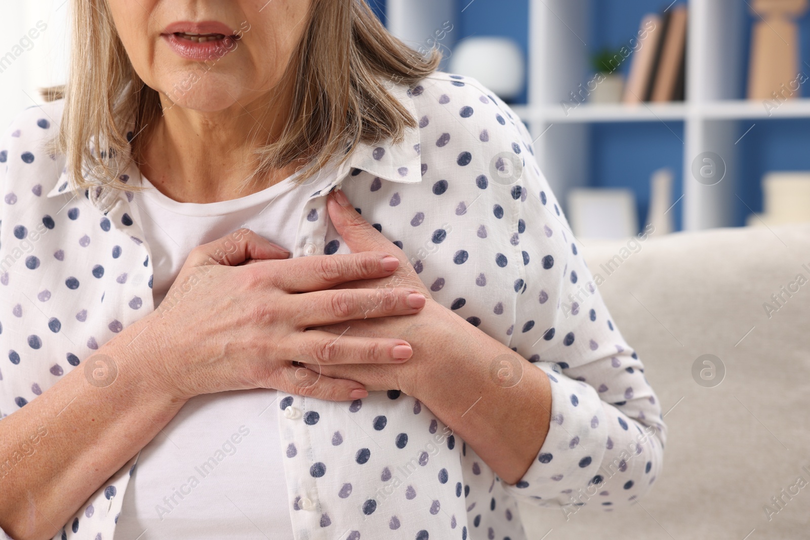 Photo of Heart attack. Senior woman suffering from pain in chest indoors, closeup