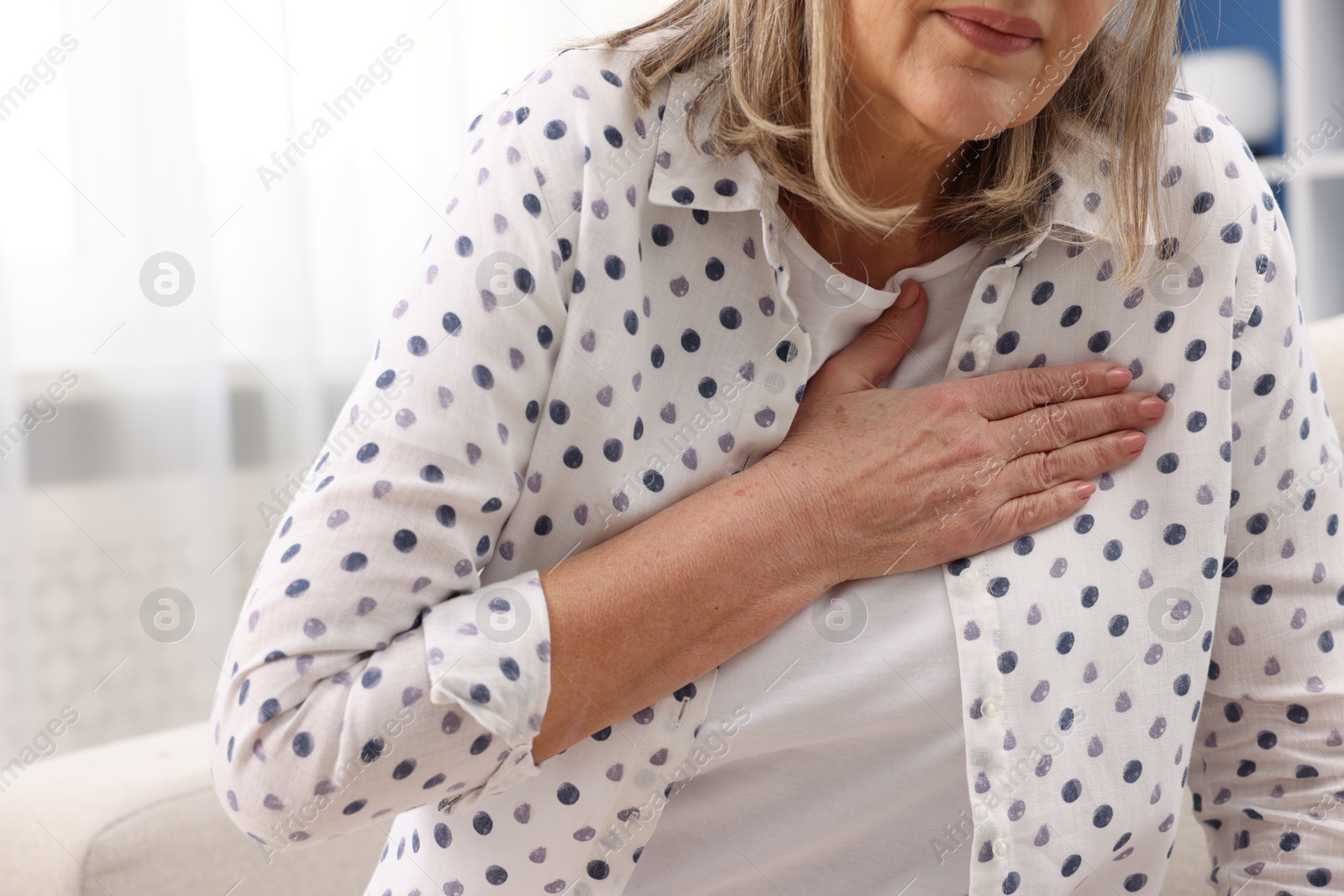 Photo of Heart attack. Senior woman suffering from pain in chest indoors, closeup