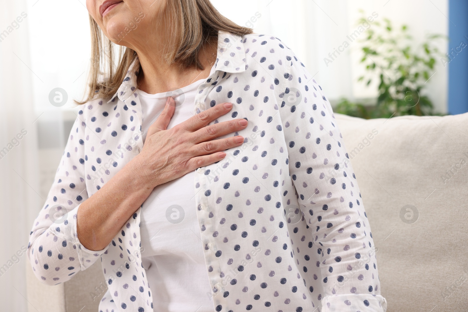 Photo of Heart attack. Senior woman suffering from pain in chest indoors, closeup