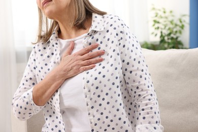 Photo of Heart attack. Senior woman suffering from pain in chest indoors, closeup