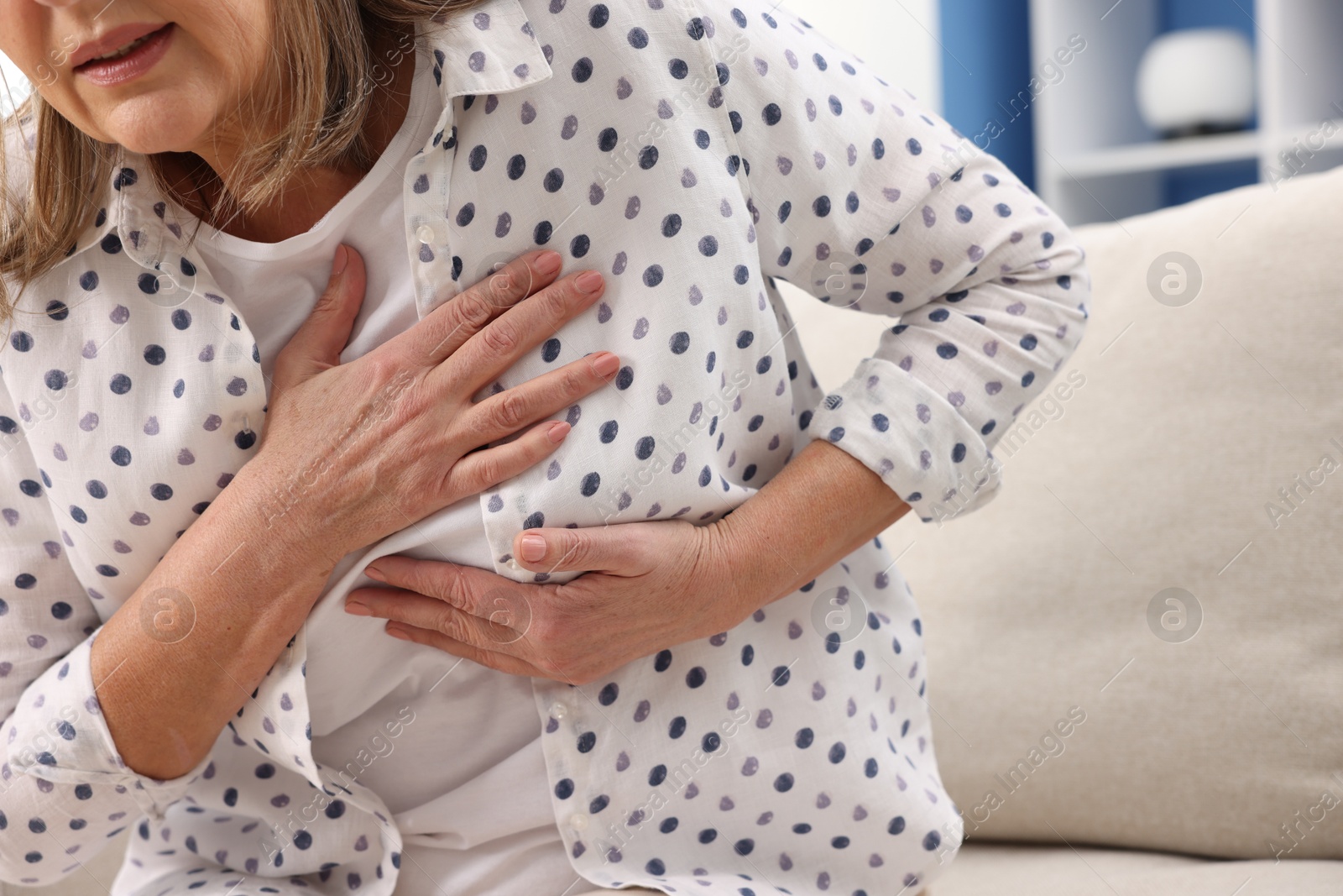 Photo of Heart attack. Senior woman suffering from pain in chest indoors, closeup