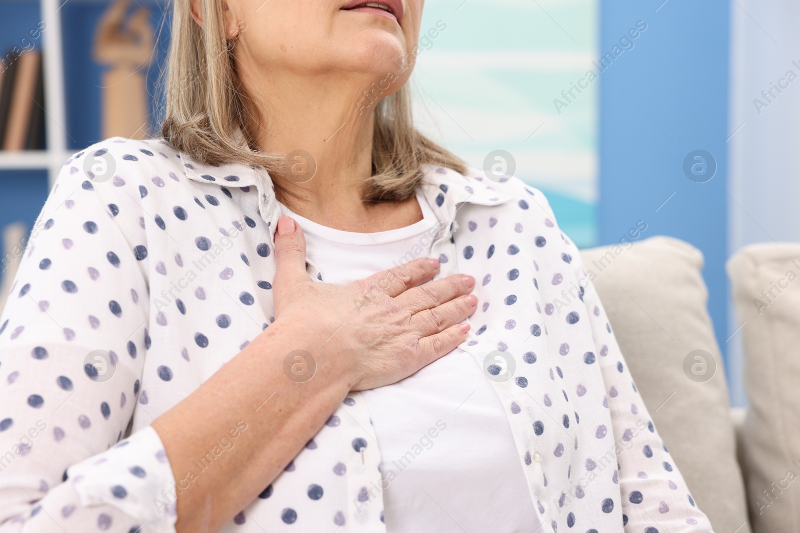 Photo of Heart attack. Senior woman suffering from pain in chest indoors, closeup