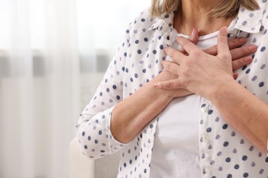 Heart attack. Senior woman suffering from pain in chest indoors, closeup. Space for text