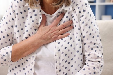 Photo of Heart attack. Senior woman suffering from pain in chest indoors, closeup