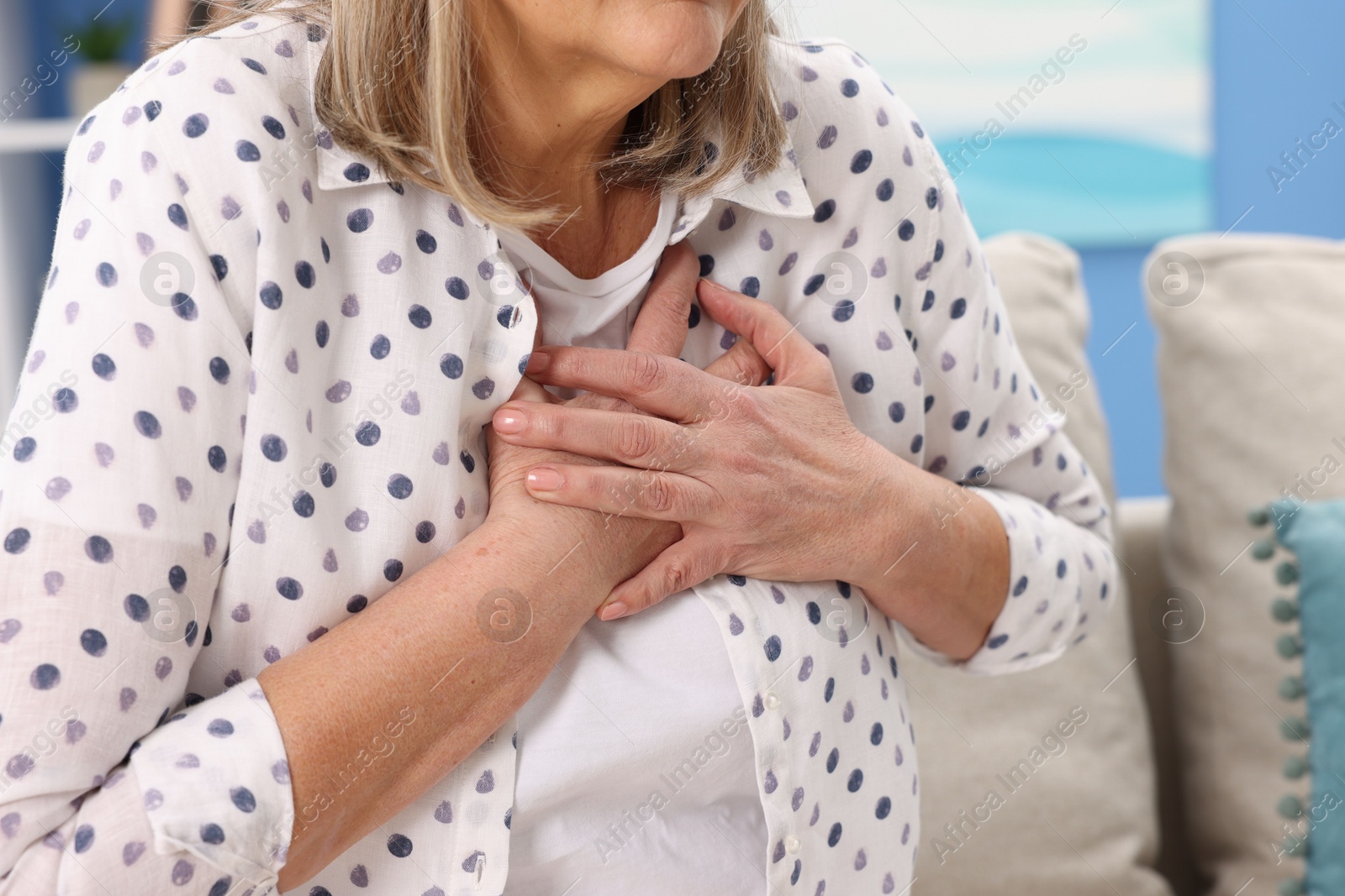 Photo of Heart attack. Senior woman suffering from pain in chest indoors, closeup