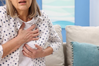 Photo of Heart attack. Senior woman suffering from pain in chest indoors, closeup. Space for text