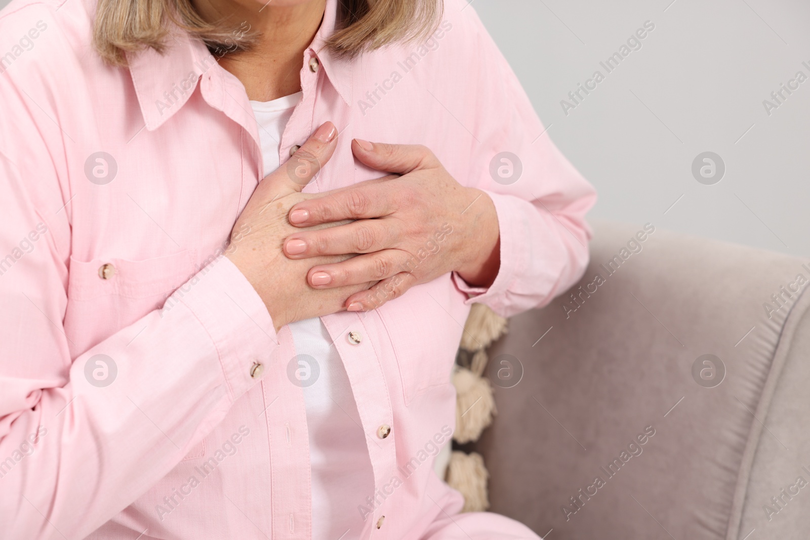 Photo of Heart attack. Senior woman suffering from pain in chest indoors, closeup