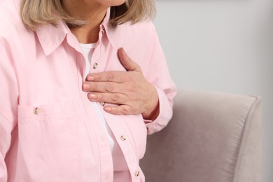 Photo of Heart attack. Senior woman suffering from pain in chest indoors, closeup. Space for text