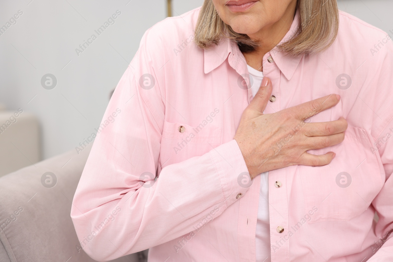 Photo of Heart attack. Senior woman suffering from pain in chest indoors, closeup