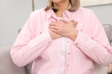 Photo of Heart attack. Senior woman suffering from pain in chest indoors, closeup