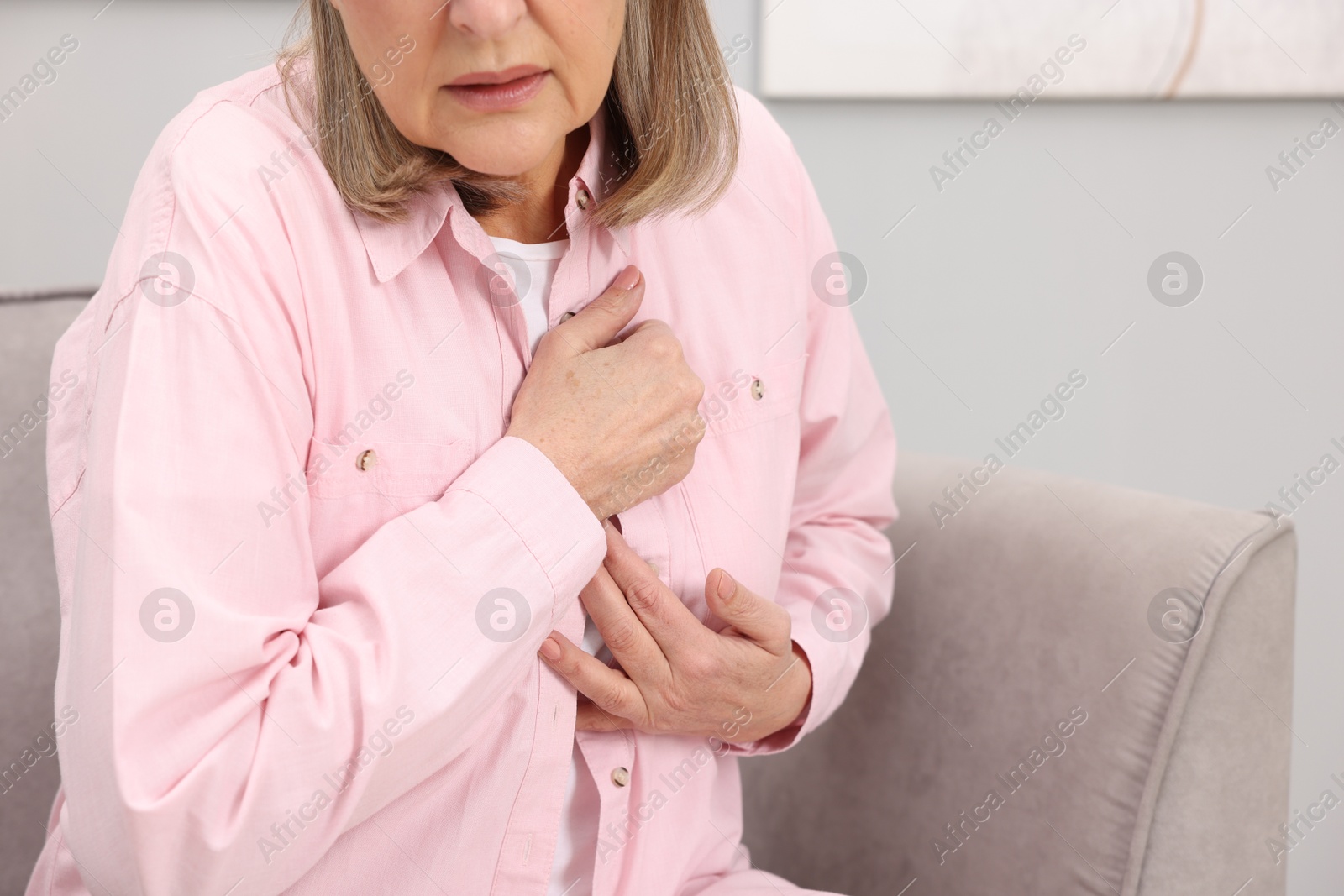 Photo of Heart attack. Senior woman suffering from pain in chest indoors, closeup