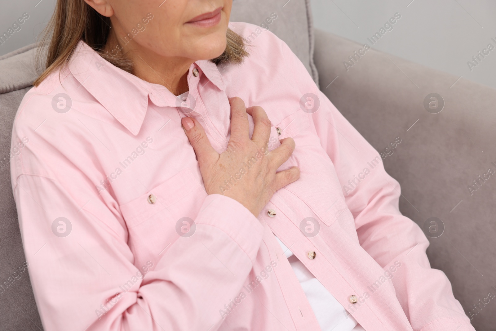 Photo of Heart attack. Senior woman suffering from pain in chest indoors, closeup