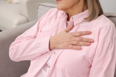 Photo of Heart attack. Senior woman suffering from pain in chest indoors, closeup