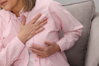 Photo of Heart attack. Senior woman suffering from pain in chest indoors, closeup