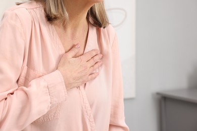 Heart attack. Senior woman suffering from pain in chest indoors, closeup. Space for text