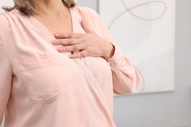 Photo of Heart attack. Senior woman suffering from pain in chest indoors, closeup