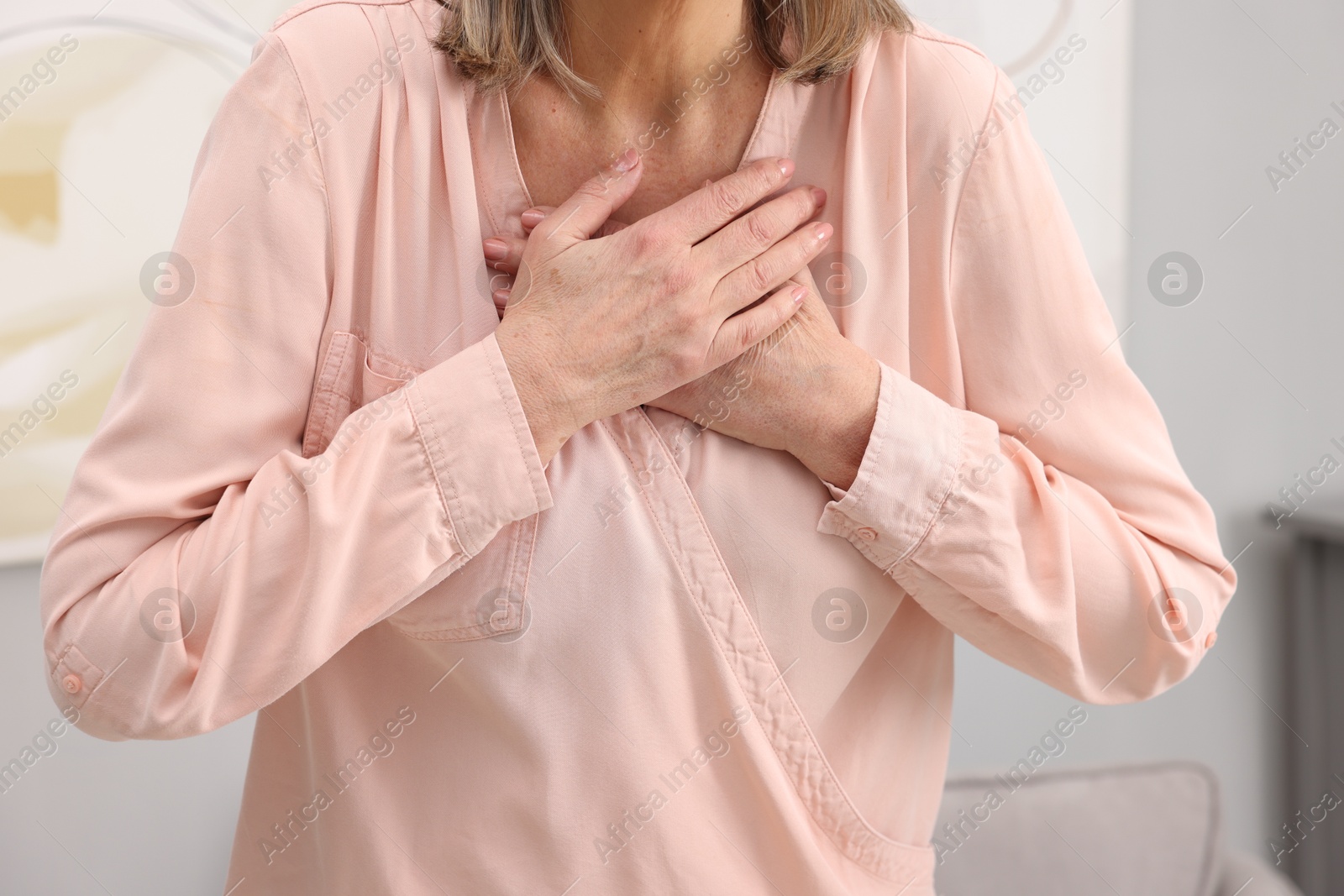 Photo of Heart attack. Senior woman suffering from pain in chest indoors, closeup