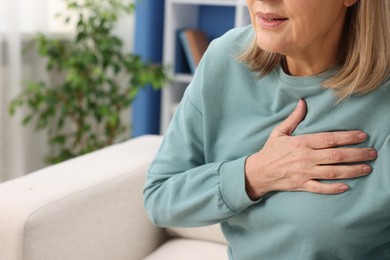 Photo of Heart attack. Senior woman suffering from pain in chest indoors, closeup. Space for text