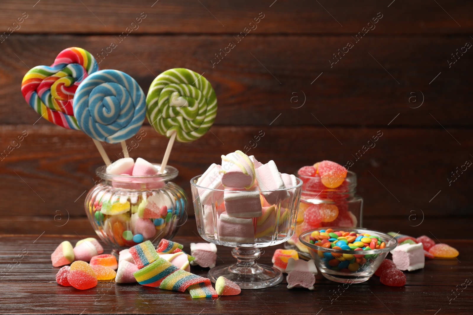 Photo of Many different tasty candies on wooden table