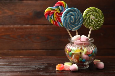 Photo of Different tasty candies on wooden table. Space for text