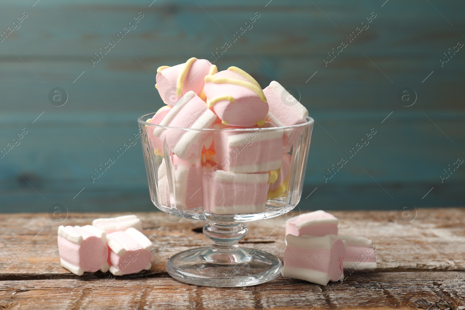 Photo of Tasty marshmallows in glass dessert bowl on wooden table, closeup