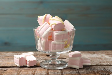 Photo of Tasty marshmallows in glass dessert bowl on wooden table, closeup