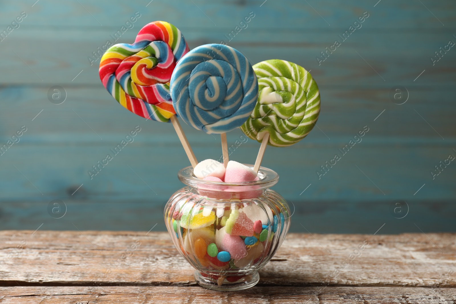 Photo of Different tasty candies in glass jar on wooden table