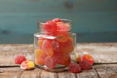 Photo of Tasty jelly candies in glass jar on wooden table, closeup