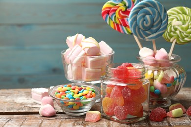 Photo of Different tasty candies on wooden table against blue background