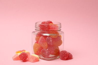 Photo of Tasty jelly candies in glass jar on pink background, closeup