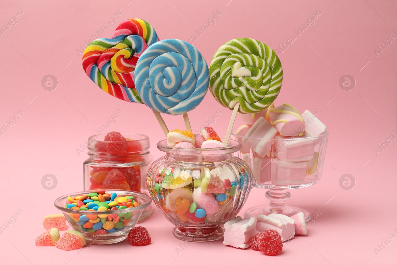 Photo of Many different tasty candies on pink background