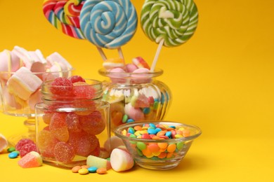 Photo of Different tasty candies on yellow background, space for text