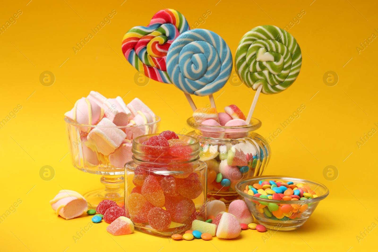 Photo of Many different tasty candies on yellow background