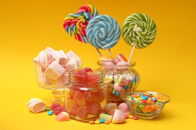 Photo of Many different tasty candies on yellow background