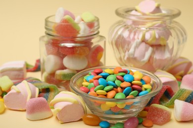 Photo of Different tasty candies on beige background, closeup