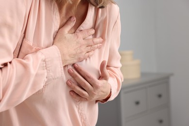 Photo of Heart attack. Senior woman suffering from pain in chest indoors, closeup. Space for text