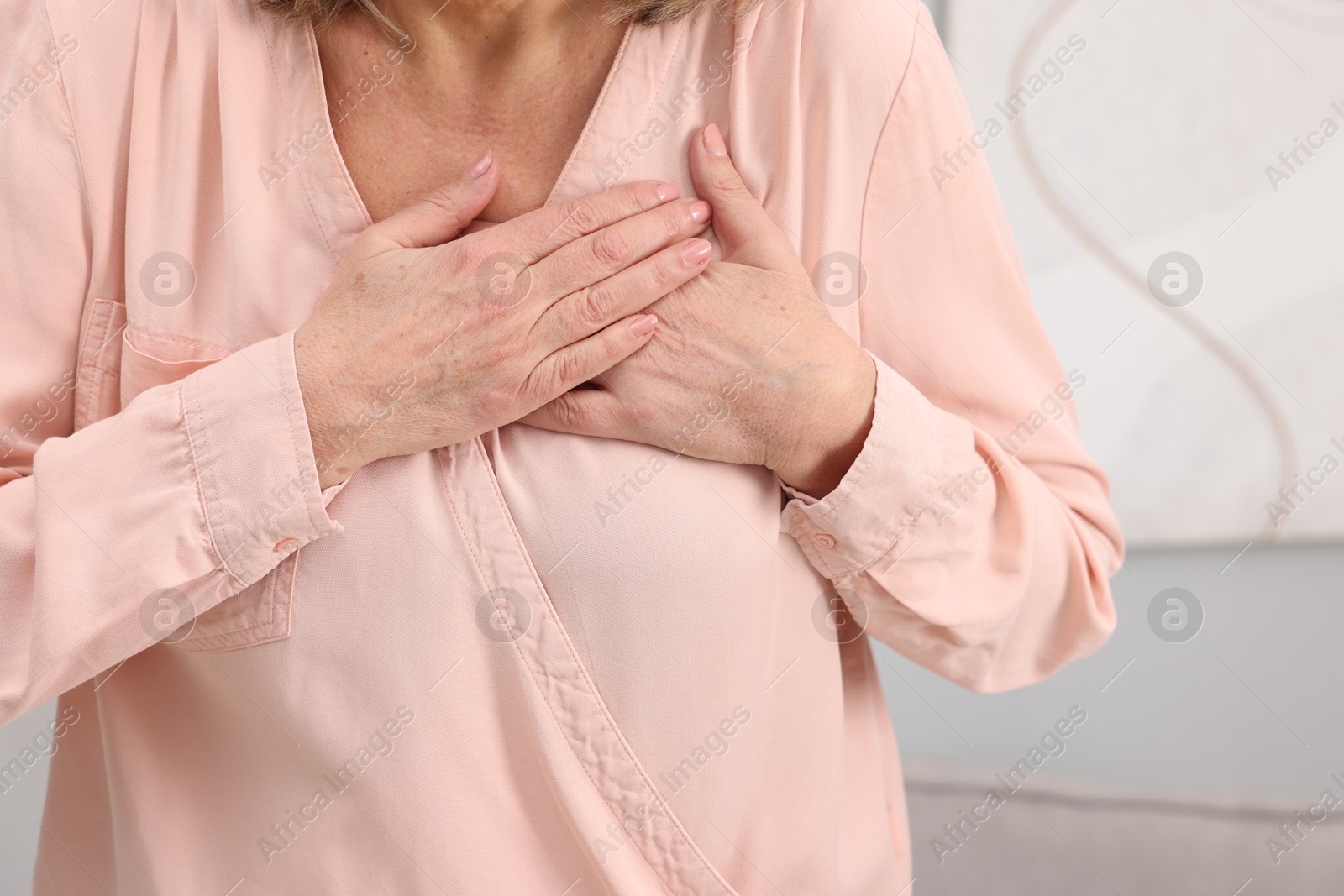 Photo of Heart attack. Senior woman suffering from pain in chest indoors, closeup