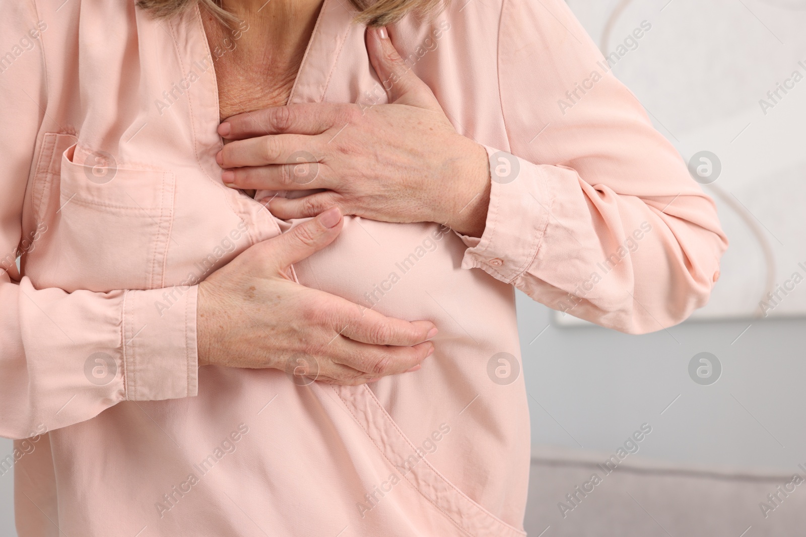 Photo of Heart attack. Senior woman suffering from pain in chest indoors, closeup