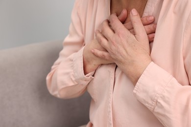 Photo of Heart attack. Senior woman suffering from pain in chest indoors, closeup