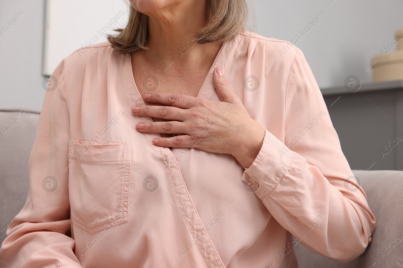 Photo of Heart attack. Senior woman suffering from pain in chest indoors, closeup